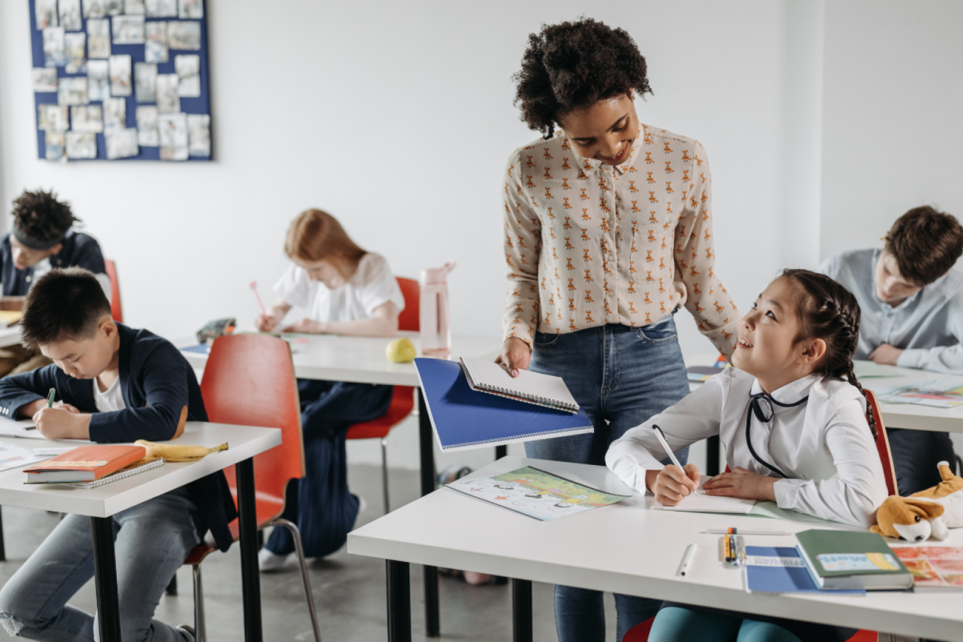 A teacher smiling as they help a student with a reading assignment